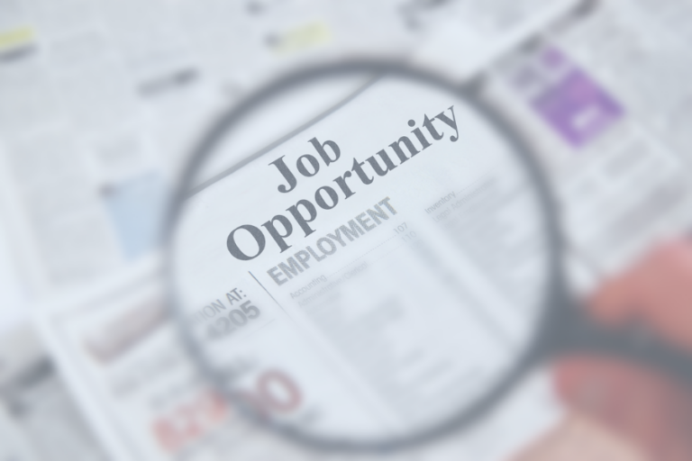 Cette image montre une loupe agrandie sur un titre de journal annonçant une "Job Opportunity" dans la section emploi. Elle illustre la recherche d'emploi et les opportunités de carrière.